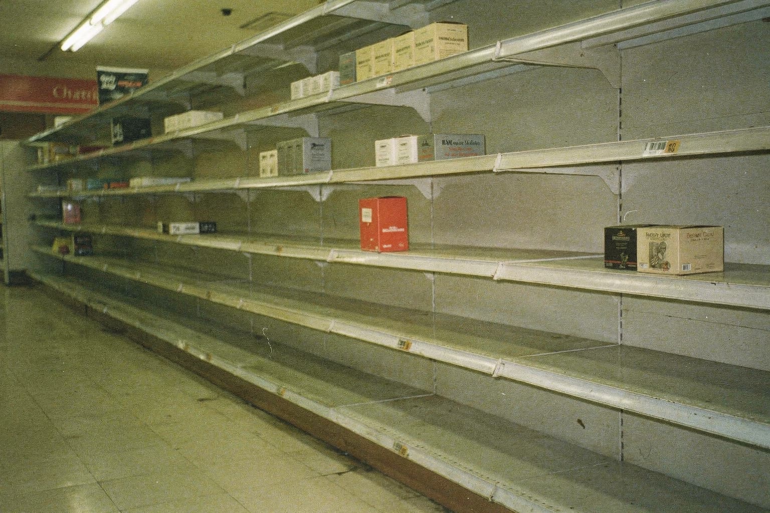 A mostly empty store shelf with one red box among muted products