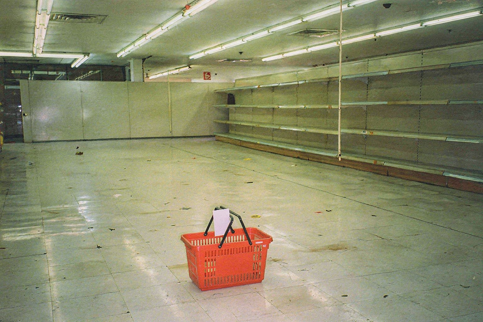 A red shopping basket sitting alone on the empty store floor