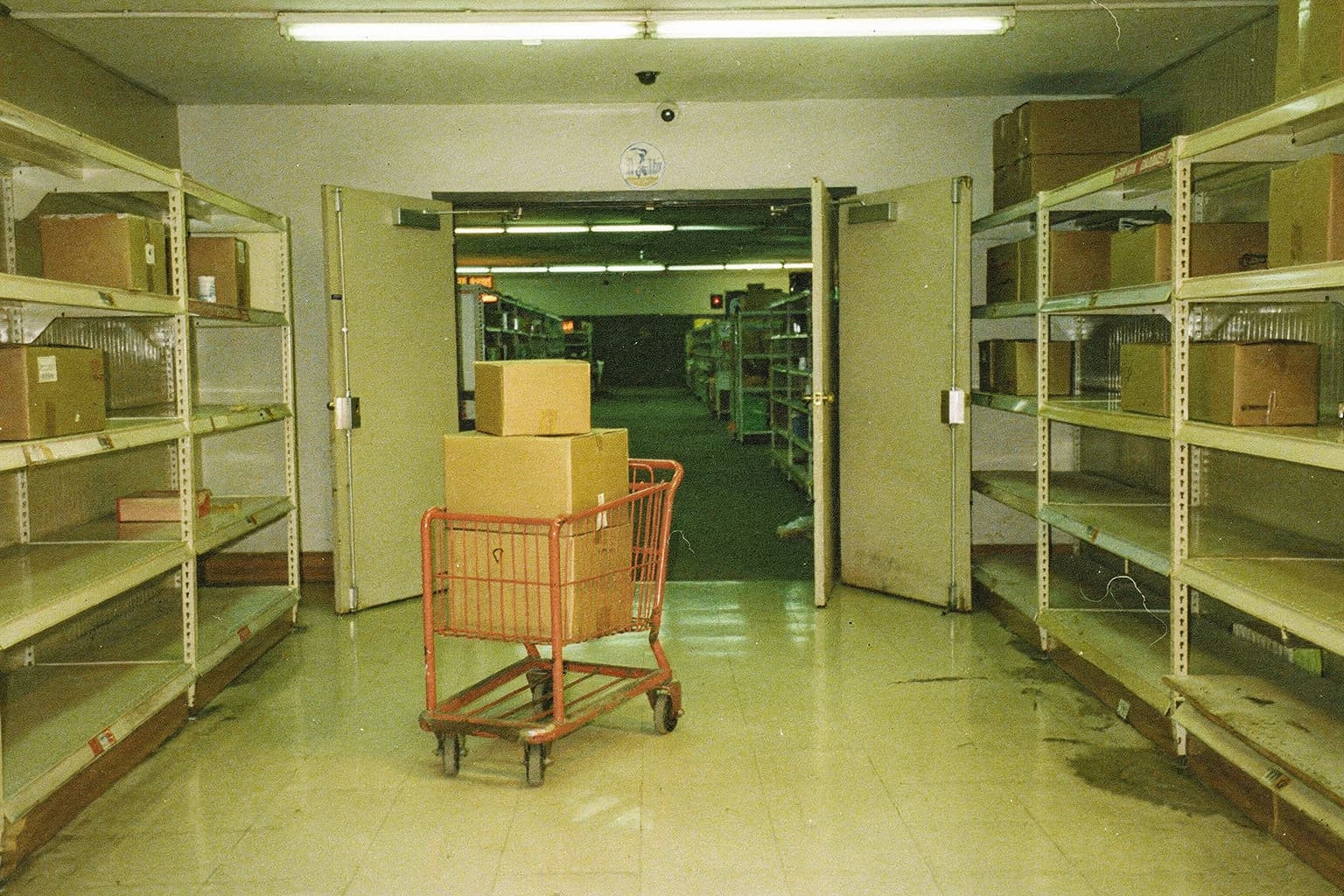 A red stocking cart carrying boxes from a retail stockroom toward the sales floor